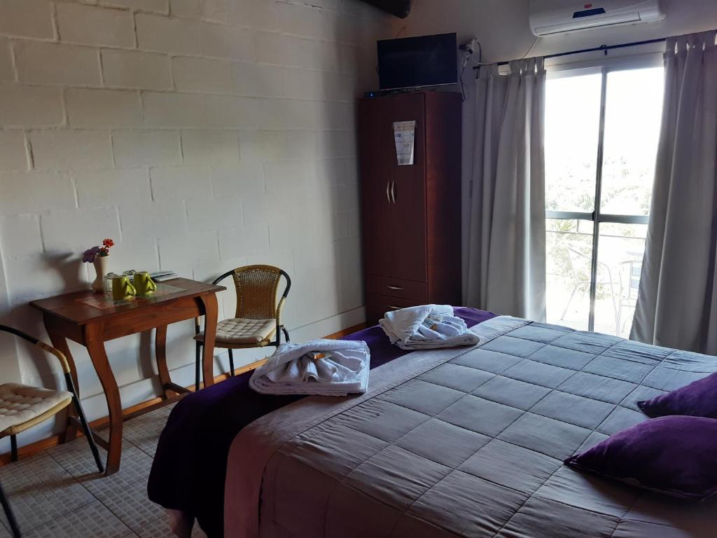 1 dormitorio con cama, mesa y ventana en Posada Miralejos en Trapiche