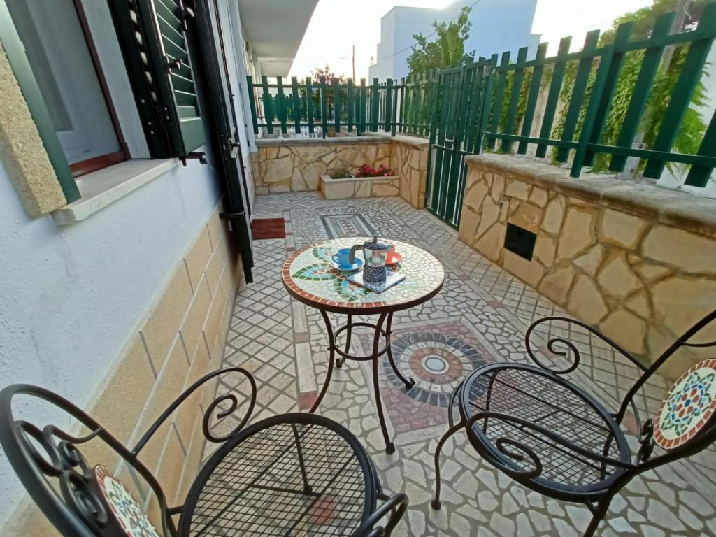 a patio with a table and chairs on a balcony at Villetta "Poesia" a 50 m dal mare con giardino e parking in Torre dell'Orso