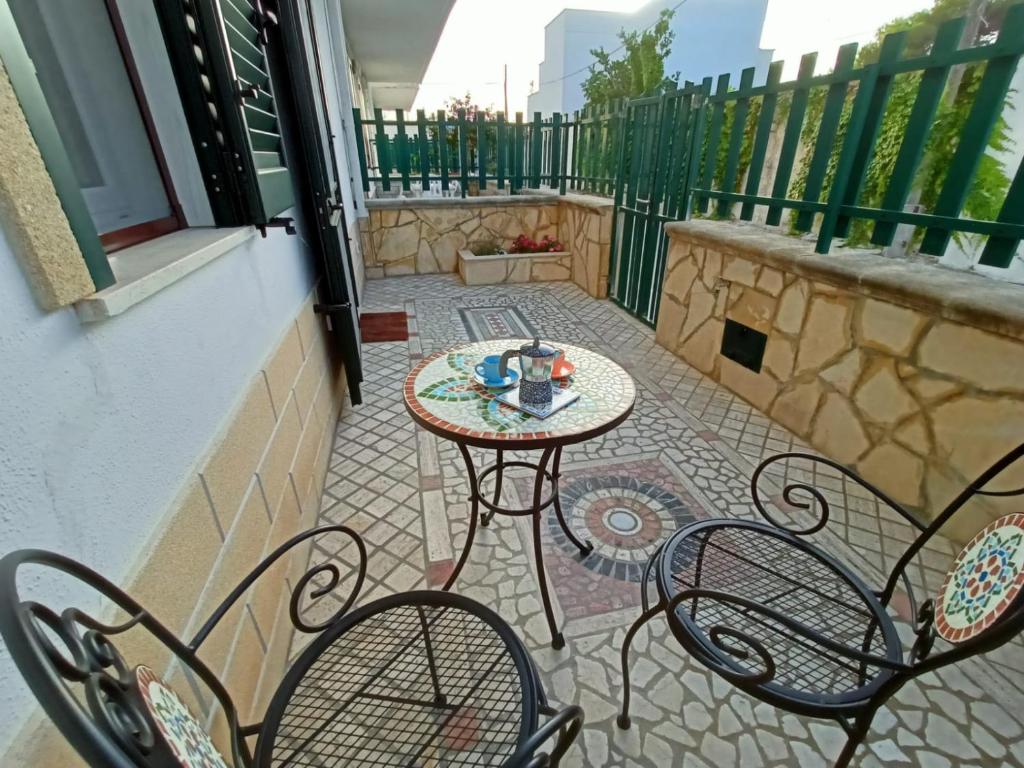 eine Terrasse mit Tisch und Stühlen auf einem Balkon in der Unterkunft Villetta Poesia 50 m dal mare con giardino e parcheggio in Torre dell'Orso