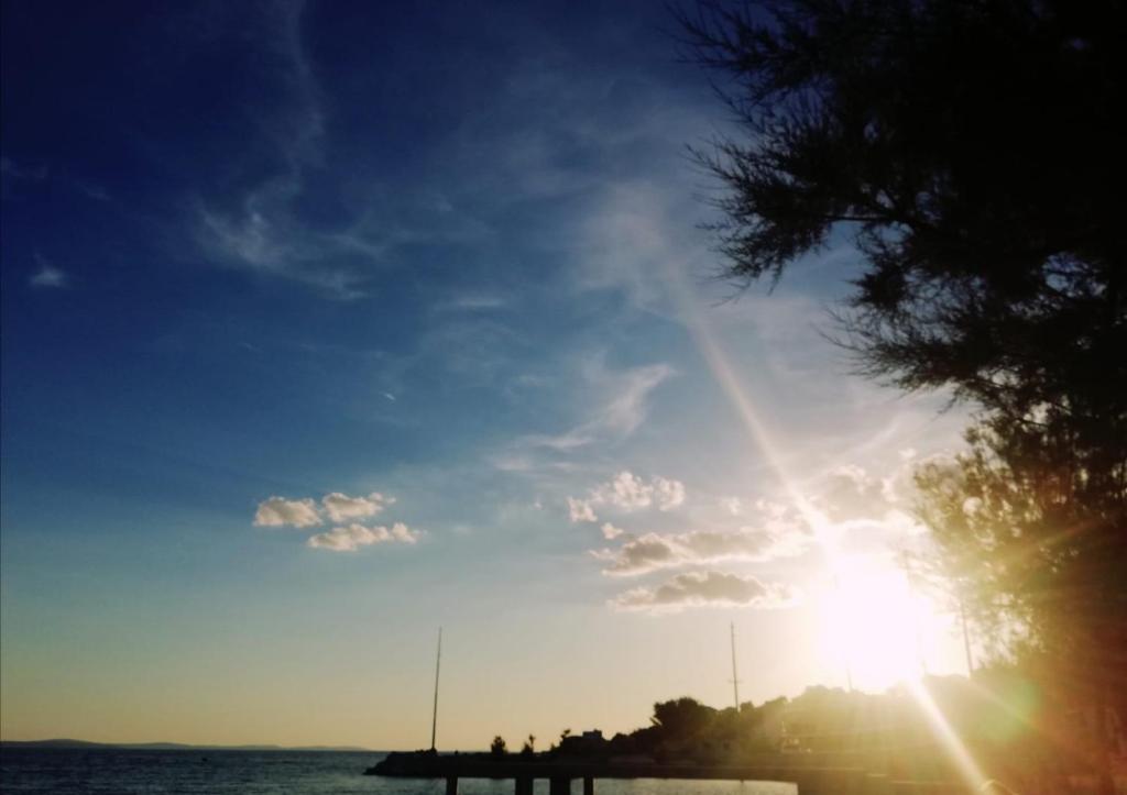 a sun shining in the sky over the water at Apartman Aria in Dugi Rat