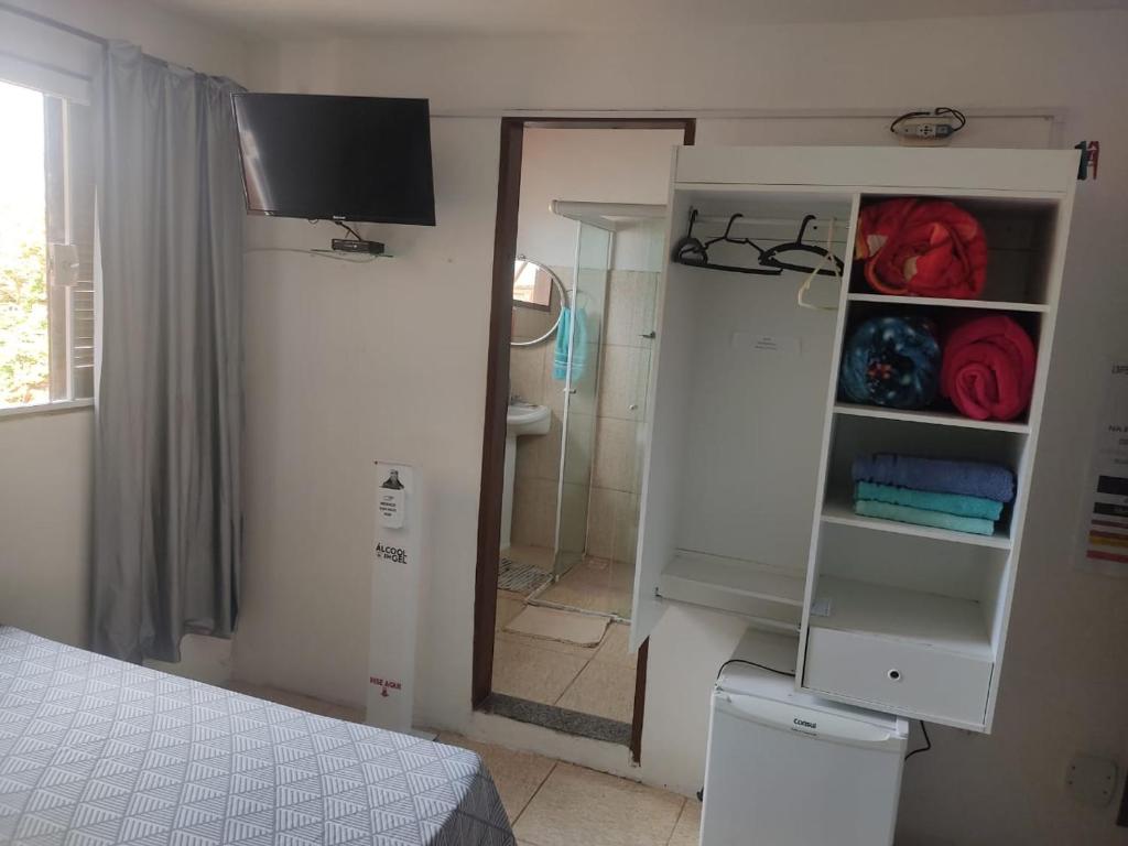 ein Schlafzimmer mit einem Bett und ein Badezimmer mit einem Spiegel in der Unterkunft Suites Pouso Familiar José e Maria in Paraty