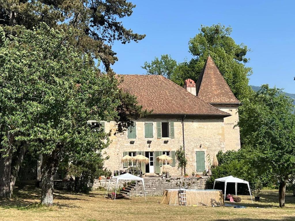 une grande maison en pierre avec des parasols en face de celle-ci dans l'établissement Domaine du Très-Haut - Château de Montanges, à Montanges