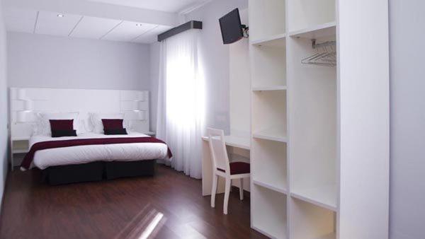 a bedroom with a bed and a desk and a chair at Hotel Pepo in Benifallet