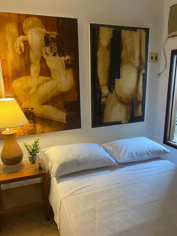 a bedroom with two paintings on the wall and a bed at Ateliê 22 in Natal