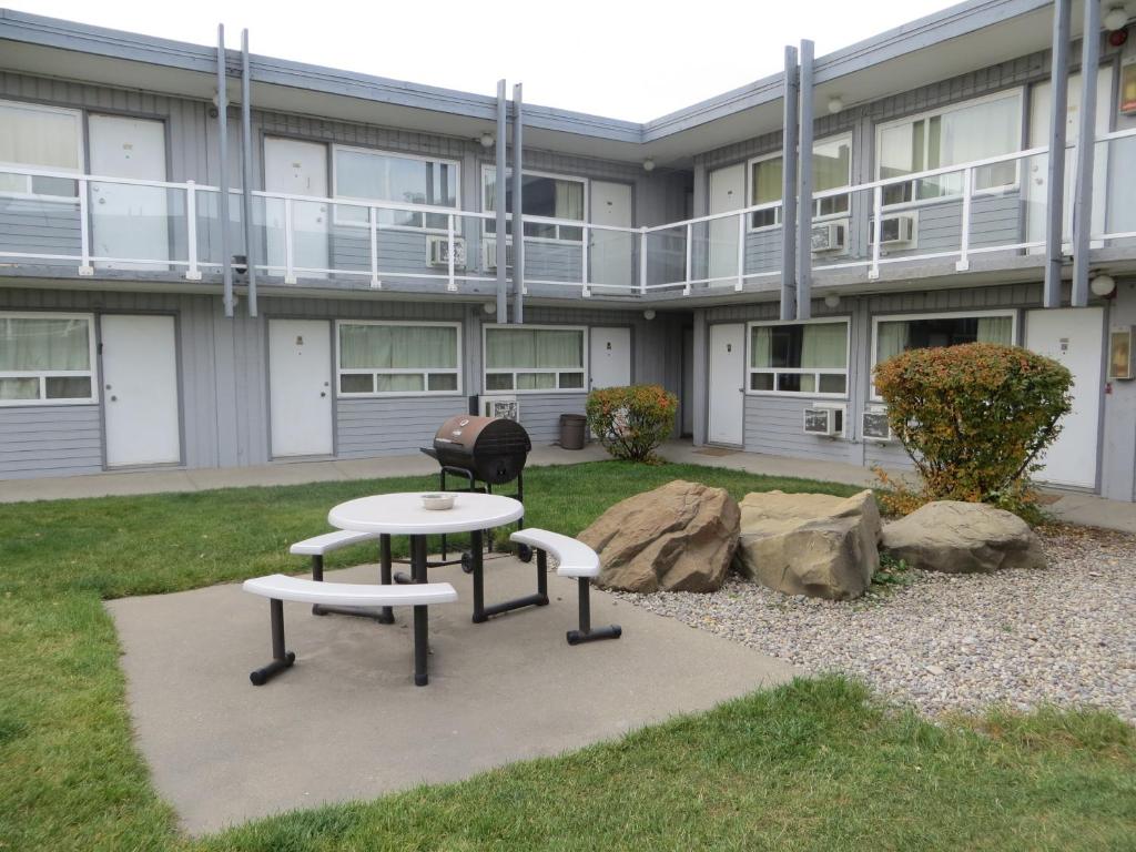 a building with two tables and a grill in a yard at Travellers Inn in Calgary