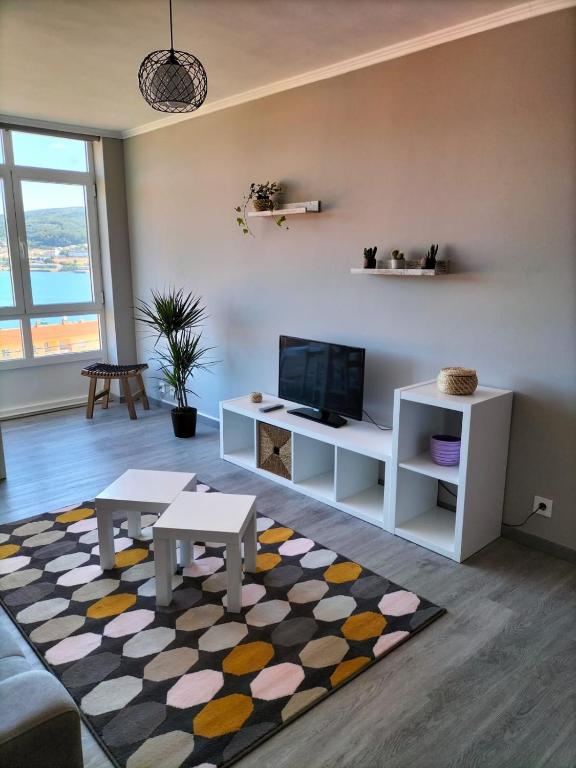 a living room with a couch and a tv and a rug at O Vendaval in Corcubión