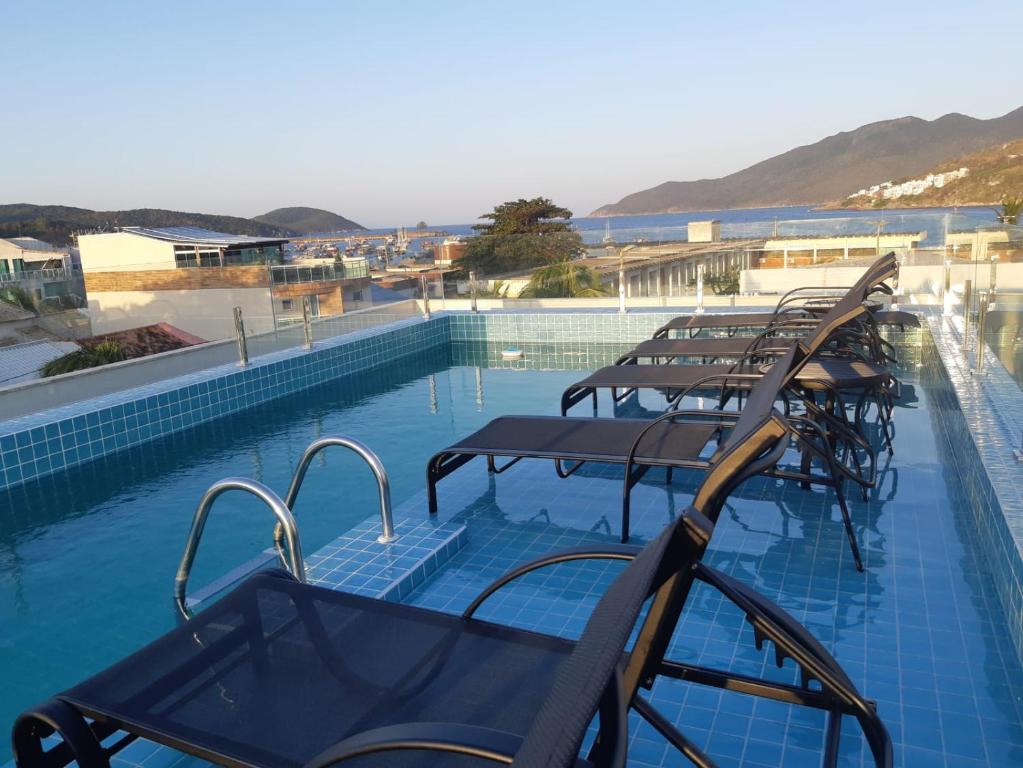 una piscina con un montón de sillas. en Pousada Areia Branca en Arraial do Cabo