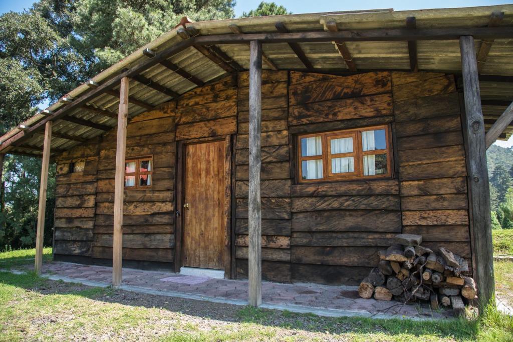 a log cabin with a door and a pile of logs at Rancho La Mesa 