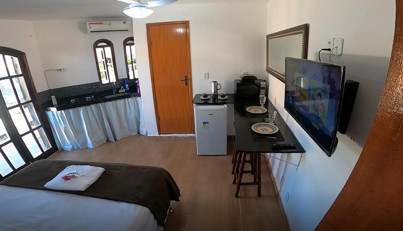 une chambre avec un lit, un bureau et une télévision dans l'établissement Melhores Suítes, à Arraial do Cabo