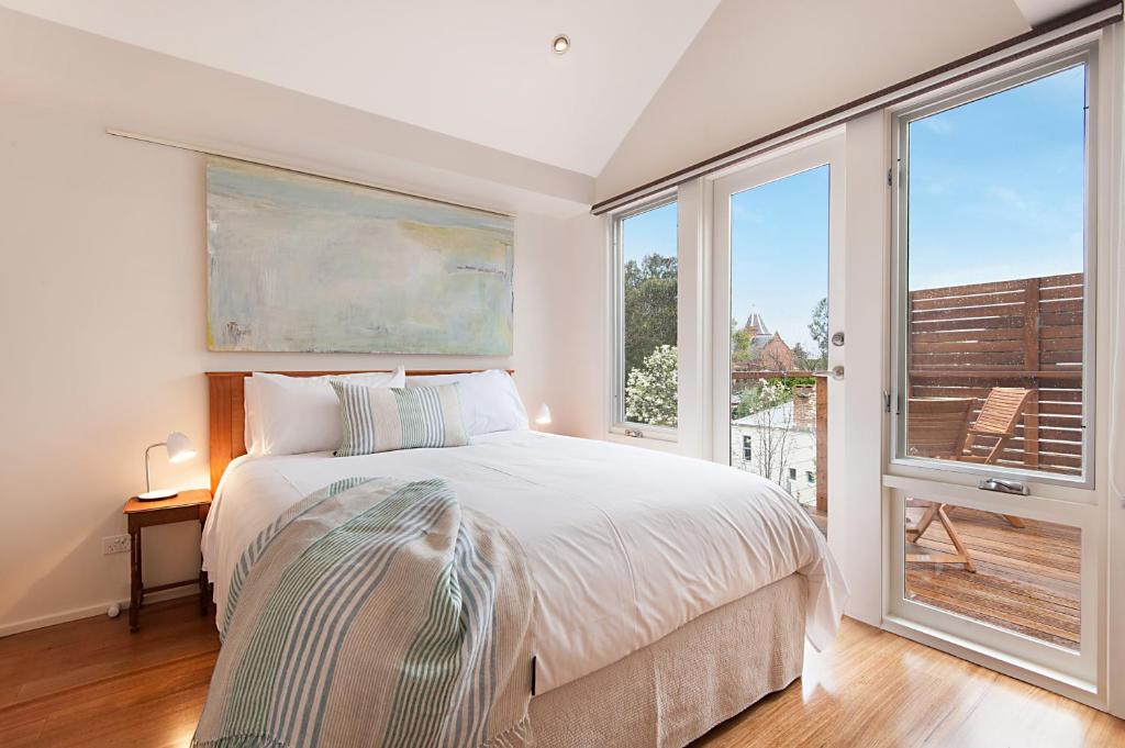 a bedroom with a bed and two large windows at Salt Loft in Queenscliff
