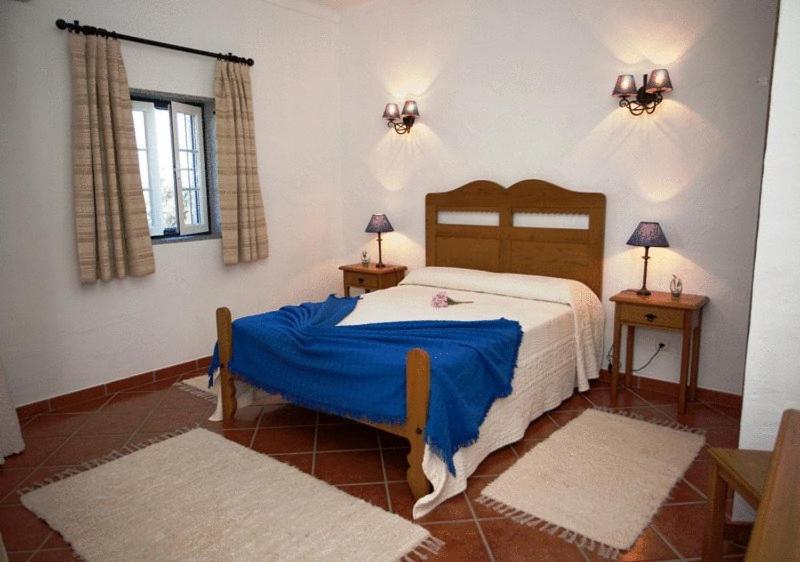 um quarto com uma cama com um cobertor azul em Naveterra-Hotel Rural em Alandroal