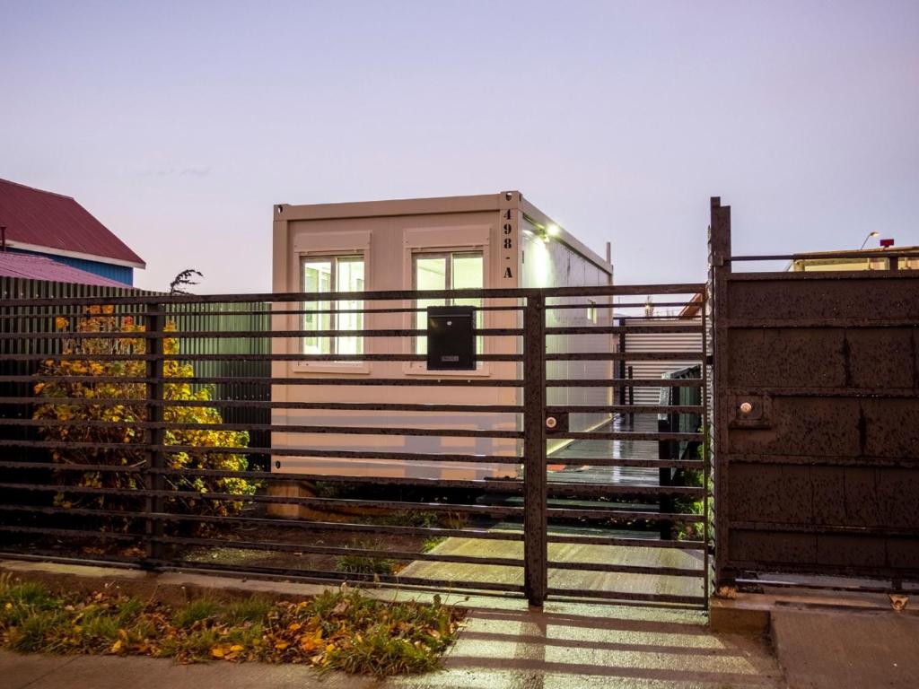 una pequeña casa detrás de una valla con una puerta en Container Departamento en Puerto Natales, en Puerto Natales