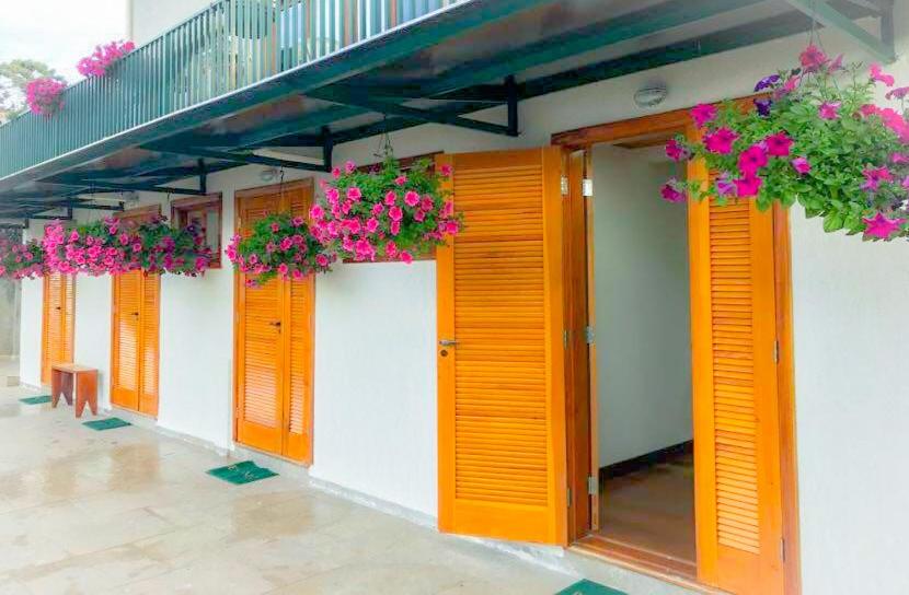 una fila de puertas naranjas con flores en un edificio en Ville de Ros I, en Campos do Jordão