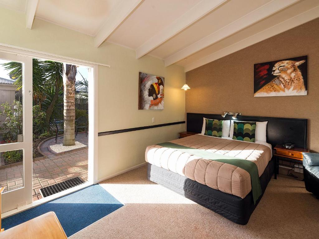 um quarto com uma cama e uma porta de vidro deslizante em MALFROY Motor Lodge Rotorua em Rotorua