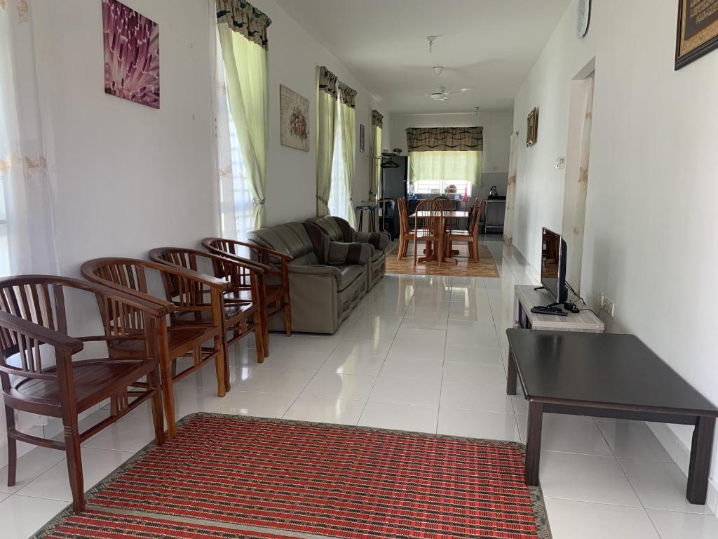 a living room with a couch and chairs and a table at SRI KENANGA HOMESTAY in Bandar Penawar