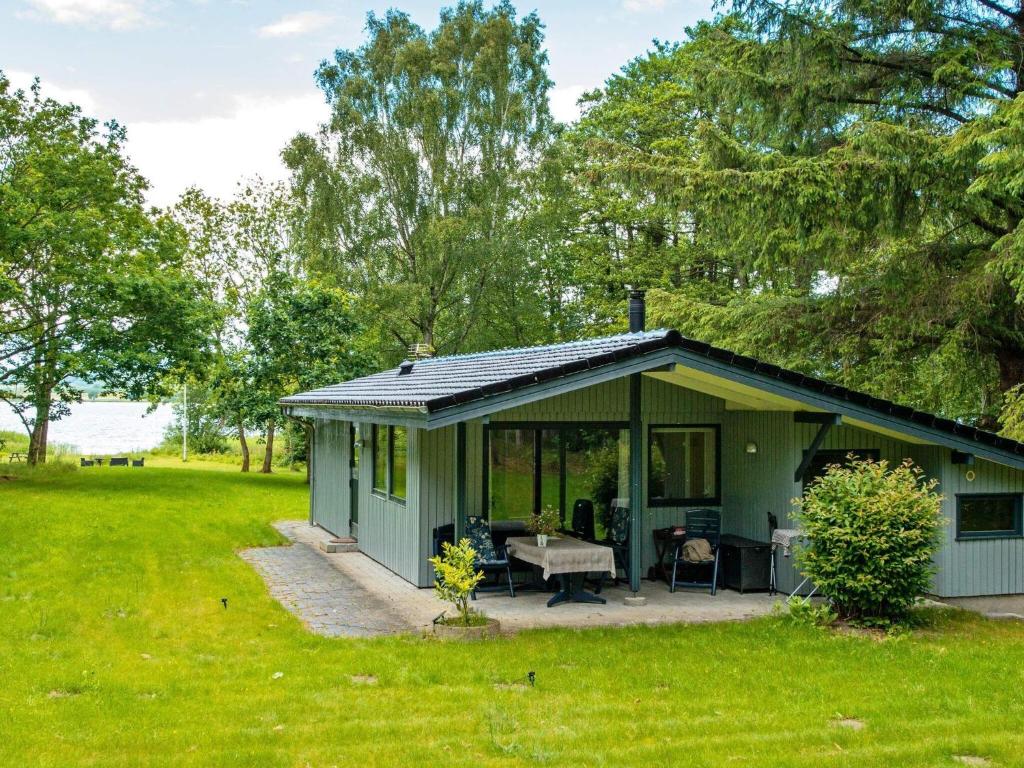 a small green house with a patio in a yard at Holiday home Skanderborg V in Skanderborg