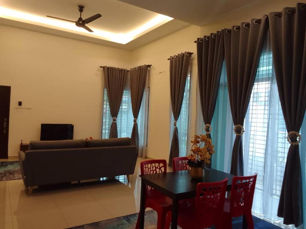 a living room with a couch and a table and chairs at HOMESTAY IMPIAN, BATU GAJAH PERAK in Kampong Paya Rengas