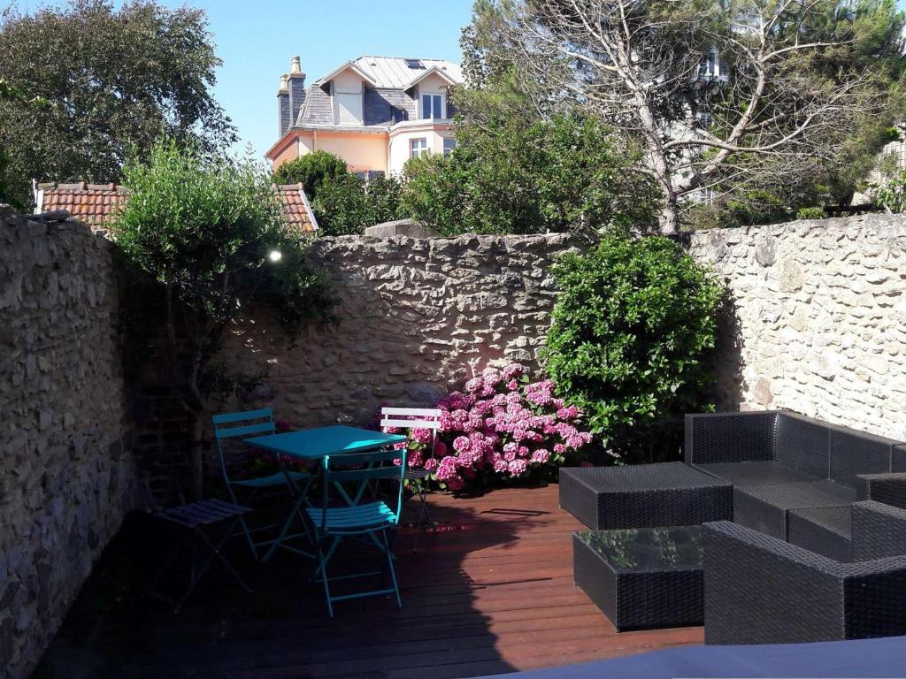 patio ze stołem, krzesłami i ścianą w obiekcie Maison cosy à 200m de la plage, 3 ch, terrasse, WiFi, proche centre, idéale pour famille - FR-1-675-7 w mieście Wimereux