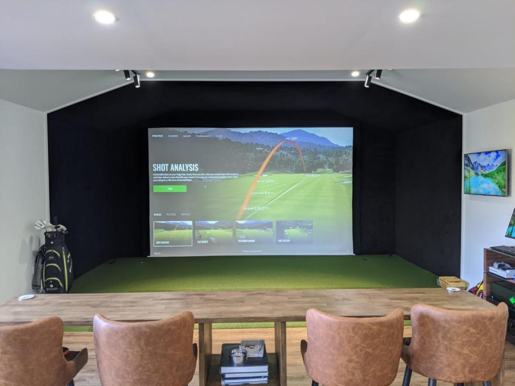 a projection screen in a room with a table and chairs at Golfers dream Guest suite with onsite golf studio available for booking by guests in Strathkinness