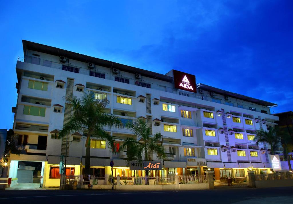 un gran edificio blanco con un cartel. en Hotel Aida en Kottayam