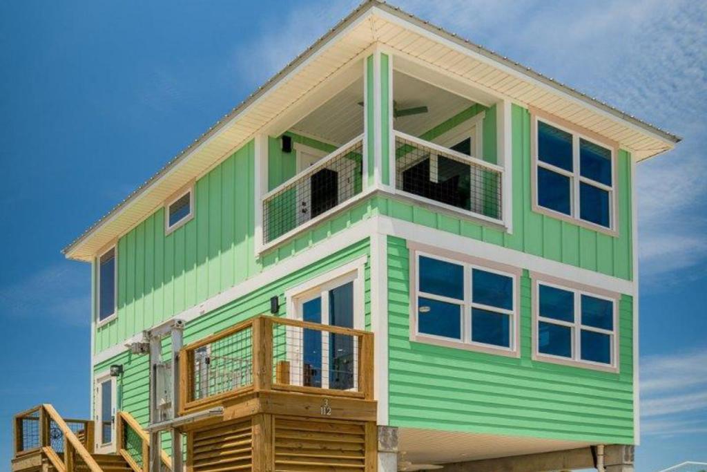 a green and white house with a balcony at Cornerstone Beachside Cottage in Mexico Beach