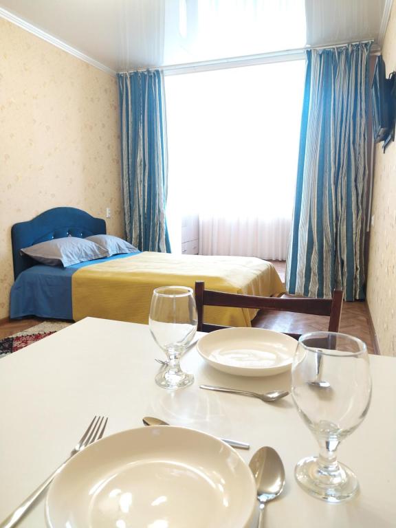 Cette chambre comprend une table avec des verres et un lit. dans l'établissement AURA on Kievskaya, 168, à Bishkek