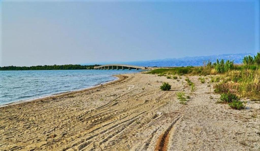 a sandy beach with a bridge in the background at Holiday home Ivana - private pool in Privlaka