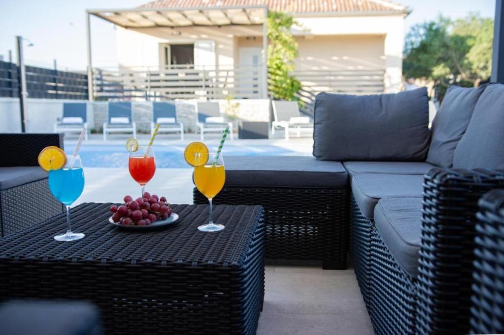 a table with two drinks and a plate of fruit at Holiday home Ivana - private pool in Privlaka