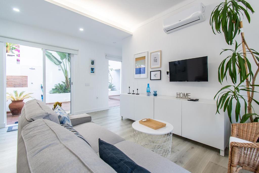 een witte woonkamer met een bank en een tv bij Guadiana River Apartment in Vila Real de Santo António