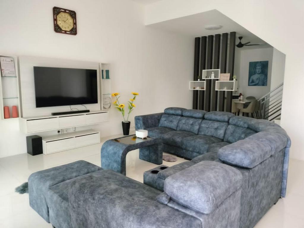 een woonkamer met een bank en een tv bij FAMILY HOLIDAY HOME in Ipoh