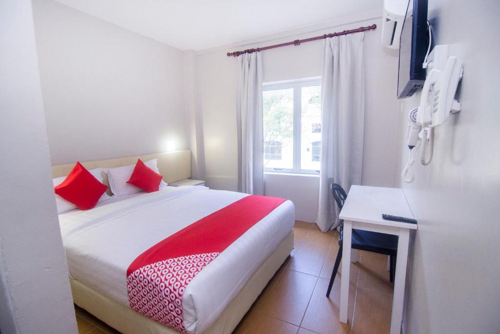 Un dormitorio con una cama con almohadas rojas y una ventana en Super OYO 897 iBC36 Business Stay, en Kuching