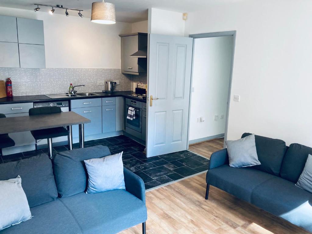 ein Wohnzimmer mit einem blauen Sofa und einer Küche in der Unterkunft 1 Bedroom Apartment - Bedworth Nuneaton Coventry in Attleborough