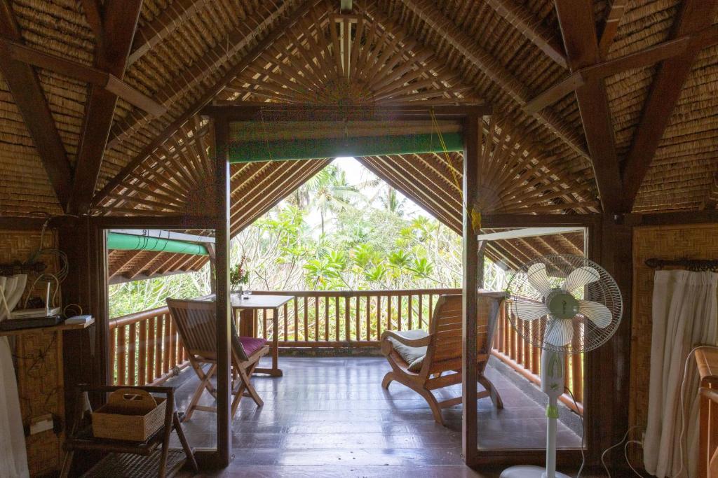 a room with a porch with chairs and a fan at Bali Firefly BnB in Ubud