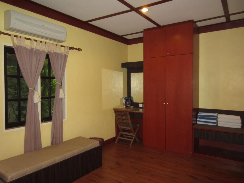 a bedroom with a bed and a desk and a cabinet at Sunset Beach Resort in Pantai Cenang