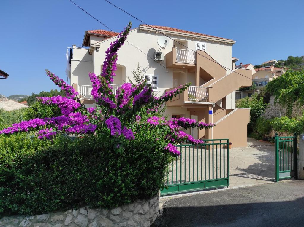 um edifício com flores roxas em frente em Holiday Residence Zvono em Mlini