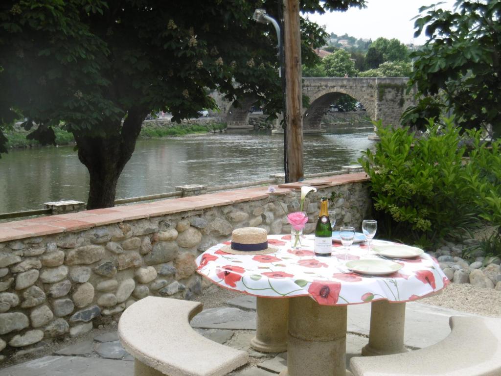 una mesa con una botella de vino junto a un río en LIMOUX RIVERSIDE GARDENs, en Limoux