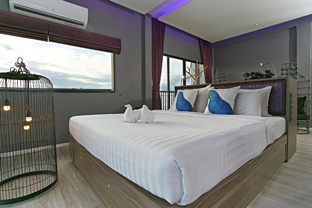 a bedroom with a large white bed with blue pillows at The Weekend Pattaya (Tweet Tweet Nest Pattaya) in Pattaya