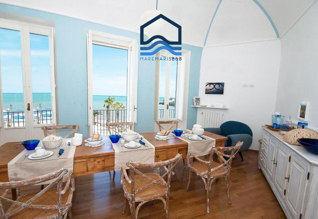 une salle à manger avec une table et des chaises et l'océan dans l'établissement Maremaris B&B, à Trani