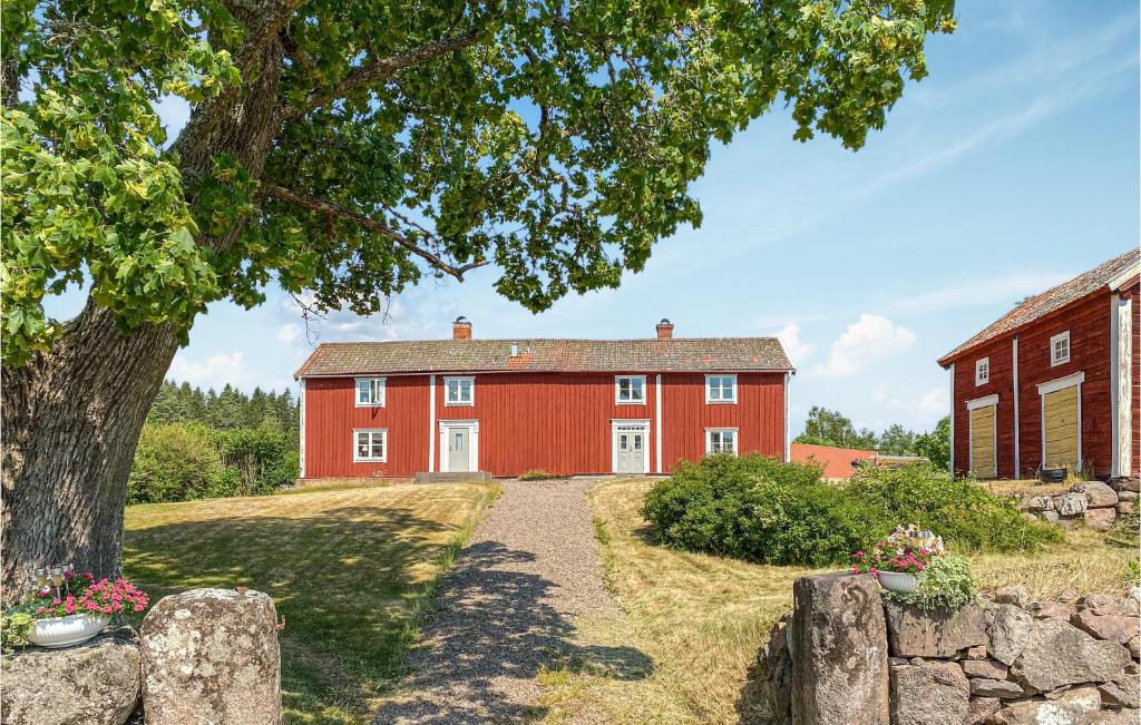 een rood huis met een boom ervoor bij Lovely Home In Kisa With Wifi in Kisa