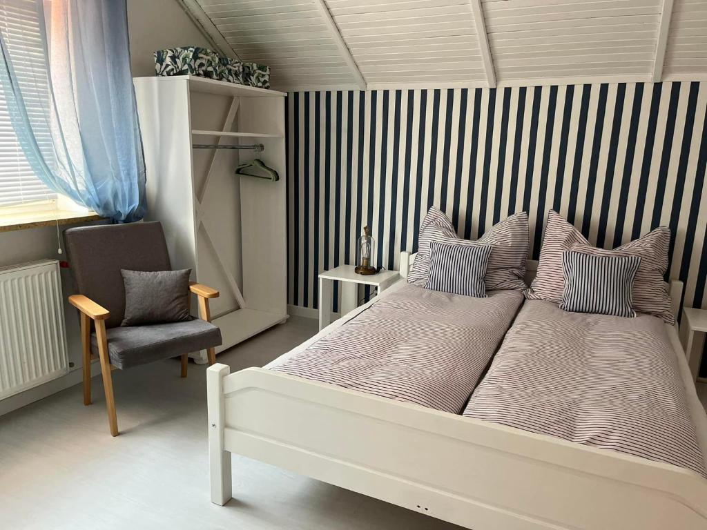 um quarto com uma cama grande e uma cadeira em Pensjonat Dom Latarnika em Grzybowo