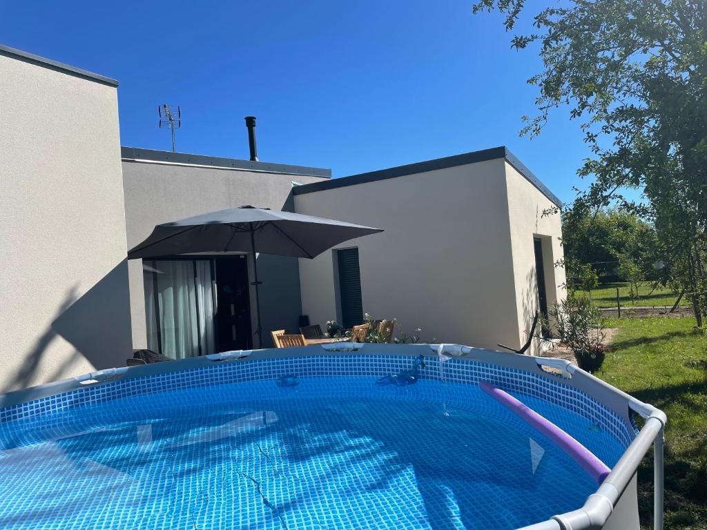 una piscina con sombrilla frente a una casa en Quiniere - Entre Lac et Forêt, en Blois
