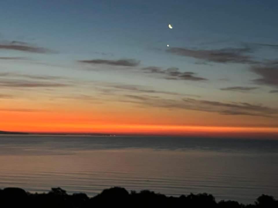 a sunset over the ocean with the moon in the sky at La vue marine II in Burgas