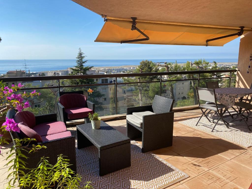un patio con sillas y mesas en un balcón en appartement Nice , jardin et mer, en Niza
