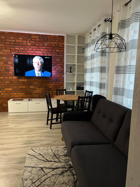 a living room with a couch and a tv on a brick wall at Przytulna kawalerka w kamienicy in Ełk