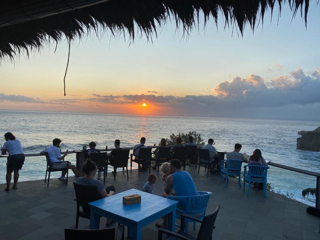 a group of people sitting at tables on the beach at sunset at Sunset Villa Lembongan in Nusa Lembongan