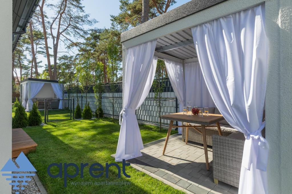 a patio with a white canopy and a table in a yard at Dom Baltic Home II Horizon Park - Aprent in Dziwnówek