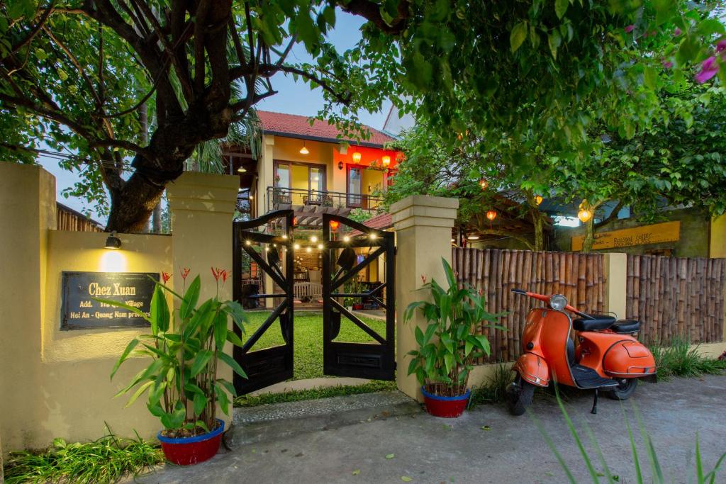 ein orangefarbener Roller, der vor einem Haus parkt in der Unterkunft Chez Xuan - Private Villa Hoian in Hoi An