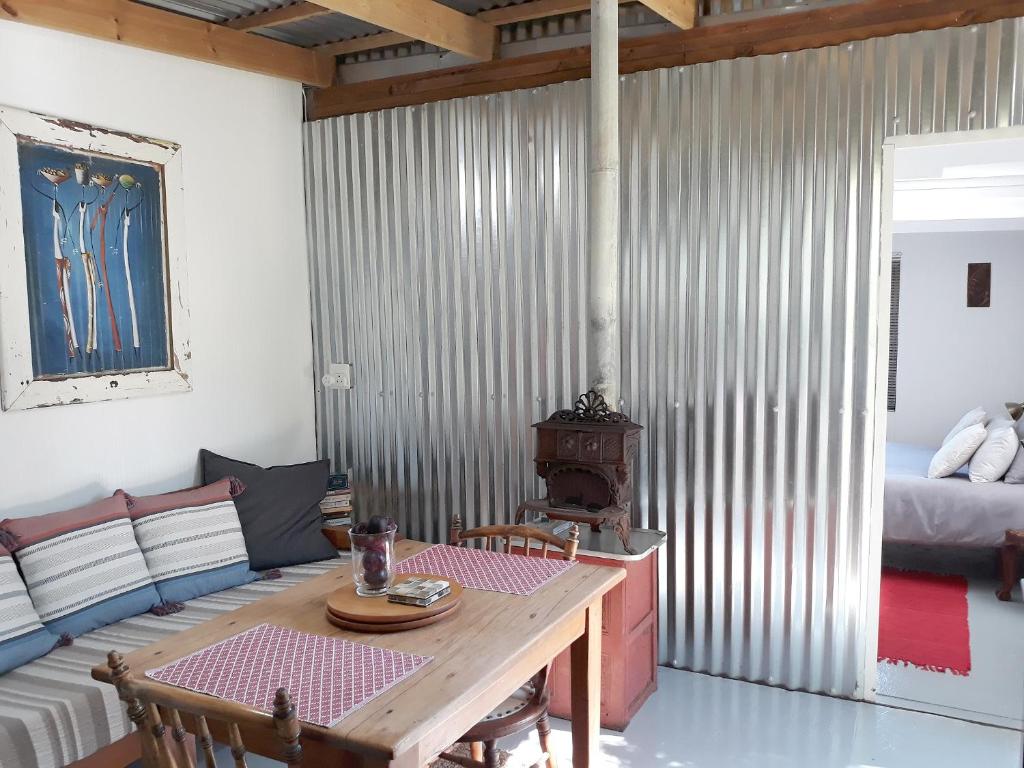 ein Wohnzimmer mit einem Tisch und ein Zimmer mit einem Bett in der Unterkunft Storms River Tin House in Stormsrivier