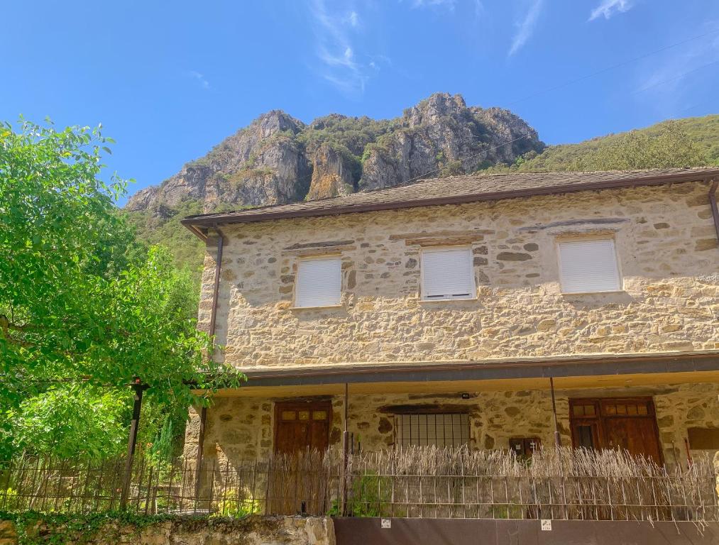 uma antiga casa de pedra com uma montanha ao fundo em Apartamento Las Medulas em Covas