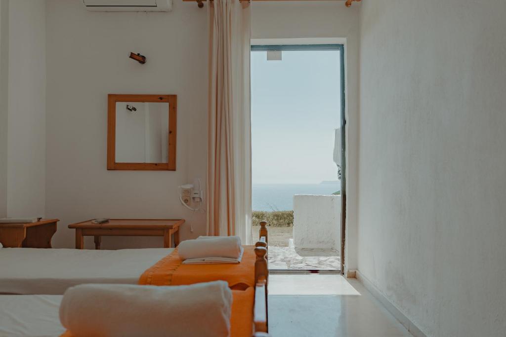 a room with two beds and a chair and a window at Arilla Beach Hotel in Perdika